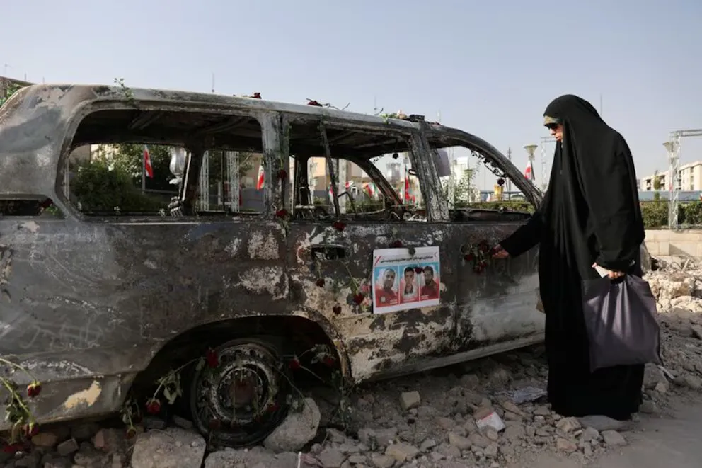 Una mujer observa una ambulancia quemada por los ataques israelíes en una calle.